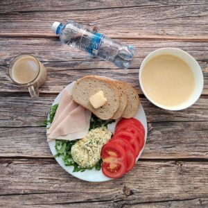 zdjęcie pokazuje dietę podstawowa Kawa zbożowa z mlekiem kasza kukurydziana Chleb mieszany pszenno-żytni Masło extra Szynka tostowa Zielona pasta jajeczna Pomidor Rukola Woda mineralna